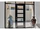 Modern black front door with glass panels and sidelight, complemented by decorative plants at 658 Falcon Summit Ct, Henderson, NV 89012