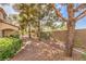 The backyard is gravel-filled and shaded with several trees and a low fence at 7270 Sheared Cliff Ln # 104, Las Vegas, NV 89149
