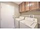 The laundry room has a washer, dryer, and wooden cabinets for storage at 7270 Sheared Cliff Ln # 104, Las Vegas, NV 89149
