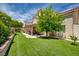 Lush backyard view showcasing a covered patio, mature tree, and a well-maintained lawn, perfect for outdoor activities at 7613 Hackensack Ct, Las Vegas, NV 89128