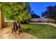 Picturesque backyard with a lush green lawn, mature trees, and decorative statues at 7613 Hackensack Ct, Las Vegas, NV 89128