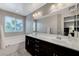 Bathroom with dark cabinets, double sinks, a large mirror, and a bathtub with a window view at 9050 W Tropicana Ave # 1080, Las Vegas, NV 89147