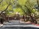 A gated community entrance featuring mature trees and landscaping at 10067 Sand Key St, Las Vegas, NV 89178