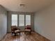 Living room area with hardwood floor, gray wall, 2 brown chairs, and 3 windows at 10067 Sand Key St, Las Vegas, NV 89178