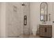 Hallway bathroom featuring a walk-in shower with elegant tilework and a modern vanity and round mirror at 18 Placa De Rei Ct, Henderson, NV 89011