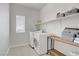 Functional laundry room with washer, dryer, shelving, and a folding table for convenience at 5742 Shadow Bend Dr, Las Vegas, NV 89135