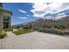 This backyard features a brick patio, small patch of grass, desert landscaping, and a mountain view at 10271 Meridian Hill Ave, Las Vegas, NV 89135