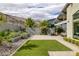 This backyard features a brick patio, small patch of grass, desert landscaping, and a mountain view at 10271 Meridian Hill Ave, Las Vegas, NV 89135
