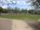 Expansive community park with lush grass, walking path, and mature trees under a partly cloudy sky at 1072 Pennyfeather Rd, Henderson, NV 89015