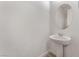 Elegant powder room with a pedestal sink, oval mirror, and stylish flooring at 12457 Sunset Sage Ave, Las Vegas, NV 89138