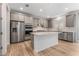 A spacious kitchen with wood flooring, stainless steel appliances, an island with seating, and white countertops at 12457 Sunset Sage Ave, Las Vegas, NV 89138