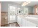 Bathroom with double sinks, neutral tile, a bright vanity, and a door leading to the pool at 2842 Mahogany Grove Ave, Henderson, NV 89074