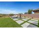 Beautiful backyard featuring stone tile accents, artificial turf, chaise lounge, and outdoor fireplace at 2913 Grande Arch St, Henderson, NV 89044