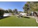 Lush backyard with green grass, mature trees and an umbrella covered outdoor dining set at 3240 W Richmar Ave, Las Vegas, NV 89139