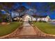 Beautifully landscaped home exterior with a charming walkway, lush lawn, and elegant lighting at twilight at 3240 W Richmar Ave, Las Vegas, NV 89139