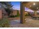 A cozy outdoor brick patio with a dining set, lush landscaping, and ambient string lights for evening relaxation at 3268 Grayson Lake Ct, Las Vegas, NV 89129