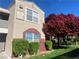Two-story condo featuring manicured landscaping and red tree at 5055 W Hacienda Ave # 2055, Las Vegas, NV 89118