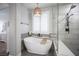 Elegant bathroom with a freestanding tub, glass shower, white shutters, and decorative lighting fixture at 5815 Pristine Falls Ave, Las Vegas, NV 89131