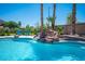 Backyard pool with rock waterfall feature and lush landscaping including mature palm trees at 5815 Pristine Falls Ave, Las Vegas, NV 89131