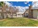 Backyard featuring a stone chimney, some trees, a grassy lawn, and a wrought iron fence at 5906 Bunch St, Las Vegas, NV 89122
