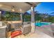 Entertain with this beautiful outdoor kitchen including stainless grill, refrigerator, and cozy seating near the pool at 6103 Stone Rise St, Las Vegas, NV 89135