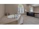 This bathroom offers a large tub, tile flooring, arched window and a vanity area with mirrors at 7687 W Pebble Rd, Las Vegas, NV 89113