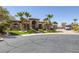 Spacious home with an arched entryway, stone facade, mature palm trees, lush lawn, and circular driveway at 7687 W Pebble Rd, Las Vegas, NV 89113