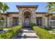Home's stone façade, arched entryway, and manicured landscaping create an inviting and impressive curb appeal at 7687 W Pebble Rd, Las Vegas, NV 89113