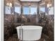 Modern bathroom boasts a standalone tub, marble accents, and natural light from the window at 9 Greely Club Trl, Henderson, NV 89052