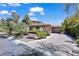 Single-story home showcasing a desert landscape, mature trees, and a concrete driveway at 9 Greely Club Trl, Henderson, NV 89052