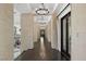 Stunning hallway with dark hardwood floors, stone columns, and elegant chandelier lighting at 9 Greely Club Trl, Henderson, NV 89052