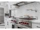 Close-up of a modern kitchen with stainless steel oven, red knobs and marble countertops and backsplash at 9 Greely Club Trl, Henderson, NV 89052