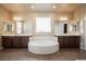 Bright bathroom featuring a soaking tub, dual vanities, and a glass block window at 9173 Whitekirk Pl, Las Vegas, NV 89145