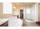 Well-lit bathroom featuring a soaking tub, glass enclosed shower, and a view into the walk-in closet at 9173 Whitekirk Pl, Las Vegas, NV 89145