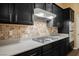 Close-up of kitchen featuring gas cooktop, tile backsplash, and dark cabinetry with modern countertops at 9173 Whitekirk Pl, Las Vegas, NV 89145
