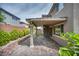 View of the property's brick-paved patio, lush landscaping, and cozy covered patio from the side yard at 9370 Burning Sage Ave, Las Vegas, NV 89149