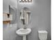 Neutral bathroom with a pedestal sink, matching oval mirror, and toilet with gray walls at 9370 Burning Sage Ave, Las Vegas, NV 89149