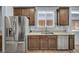 Kitchen featuring stainless steel refrigerator, stainless steel sink and dishwasher, and brown wood cabinetry at 9370 Burning Sage Ave, Las Vegas, NV 89149