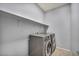A laundry room featuring a modern gray front-loading washer and dryer with a white shelf above at 9370 Burning Sage Ave, Las Vegas, NV 89149