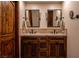 This bathroom has a double vanity with wood cabinets and travertine floors and backsplash at 1450 Rancho Cir, Las Vegas, NV 89107