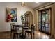 A dining area near glass paneled doors and an arched walkway is brightly lit with a round table and cushioned seating at 1450 Rancho Cir, Las Vegas, NV 89107