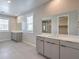 Well-lit bathroom featuring double sink vanity, large mirrors, and neutral tile flooring at 5913 Flowering Hill Ct, Las Vegas, NV 89131