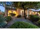 Stunning landscaped front yard with lush green bushes, desert plants, and mature trees at dusk at 7416 Redhead Dr, North Las Vegas, NV 89084