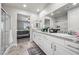 Bright, white bathroom with granite countertops and dual sinks next to a bedroom at 9068 Lennon Ln, Las Vegas, NV 89113
