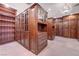 Spacious walk-in closet with custom wood cabinetry, glass-front display cases, and a decorative chandelier at 15 Rue Du Rivoli Pl, Henderson, NV 89011
