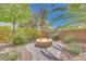 Relaxing backyard area featuring a stone fire pit and lush greenery at 7908 Morning Gallop Ct, Las Vegas, NV 89131