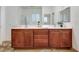 Bathroom featuring double sink vanity, large mirror, and wood cabinets at 7908 Morning Gallop Ct, Las Vegas, NV 89131