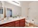 Bright bathroom featuring a double sink vanity with cherry wood cabinetry and a shower over tub at 7908 Morning Gallop Ct, Las Vegas, NV 89131