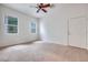 Bright carpeted bedroom with a ceiling fan, windows, and a white painted door at 7908 Morning Gallop Ct, Las Vegas, NV 89131