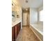 Bathroom featuring double sinks, wooden cabinets, a bathtub, and a separate door at 8920 Appellation Ave, Las Vegas, NV 89148